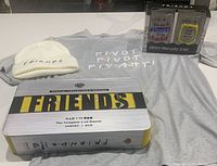 Lot contents including Friends Complete Series box set, two collectible glasses, gray women's XL T-shirt, white knit cap.