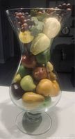 Clear large glass vase filled with colorful faux fruit arrangement, showing side view and shape of the vase