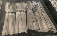 Homestyles stainless steel cutlery set arranged showing forks, spoons, and knives separated in groups on a dark surface.