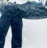 Photo of navy blue activewear jacket and bottoms laid flat on white surface showing set details and material texture.