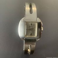 Top down view of vintage Seiko women's watch showing silver rectangular dial and hinged band with cutouts