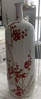 Side view showing the white porcelain vase with detailed red floral branch design.