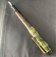 Side angle view of the vintage fountain pen showing marbled green and brown body with silver nib and gold-tone clip.