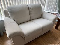 Front view of the ivory leather loveseat showing overall shape and seating area