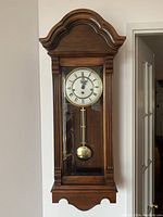 Full front view of wooden wall-mounted clock hung on wall
