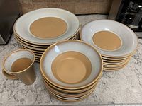 Full view of stacked plates, bowls, and mugs showing color pattern and quantity.