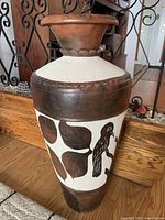 Full view of decorative floor vase showing brown and off-white painted leaf and bird pattern on side with textured detail around neck and wide opening at top.
