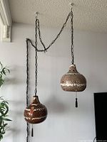 Overall view of both pendant lights suspended by black metal chains