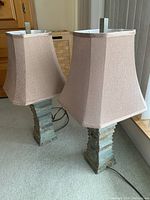 Pair of table lamps shown fully assembled with beige/taupe textured fabric shades and stone-like shale style bases, standing on carpet.