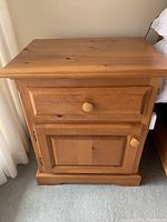 Front view of pine nightstand showing drawer and cabinet door