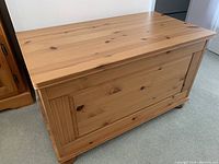 Pine storage chest front view showing natural wood finish and decorative paneling.