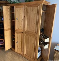 Full front view of large solid pine wood cabinet with doors open showing interior shelves and small storage boxes.