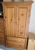 Full view of the solid pine wood wardrobe closed with visible wood knots and natural finish.