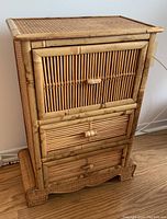 Front view of the rattan drawer unit showing the three drawers made from bamboo and woven rattan with bamboo handles and a decorative base.