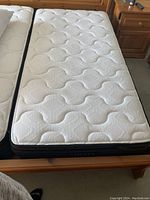 Top surface view of the twin mattress showing the white textured patterned topper with no visible stains or damage on the main sleeping area.