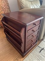 Side view showing wooden side table with built-in magazine rack and four drawers on the side with round wooden knobs.