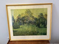 Front view of framed print showing gold-tone frame, white mat, and green landscape scene