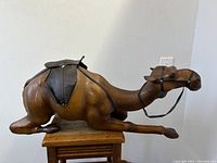 Side view of large camel sculpture showing detailed leather texture, saddle and harness.