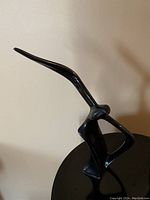 Black lacquer stylized seagull side profile with long pointed beak and open body form on a base
