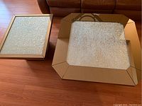 View from above showing the coffee table and end table on a hardwood floor, highlighting the mirrored and textured glass surfaces.