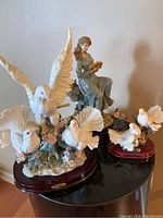 Wide shot showing all three statues on display against a beige wall, on a dark surface.