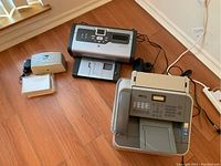 Photo showing all three devices: Brother MFC-7240 fax machine with handset, HP Photosmart 7760 printer, HP Photosmart 325 printer with noticeable discoloration.