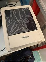 Toshiba label maker device with off-white body and black top labeled "Status". The device is somewhat worn.