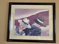 Framed vintage Ferraro art print showing two women wearing wide-brimmed hats and facing sideways, with one woman in white hat and the other in black.