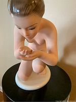 Top front view of porcelain woman kneeling statue showing face and cupped hands.