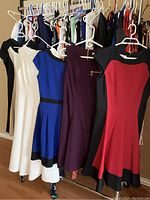 Dresses on rack showing various colors including blue, red, burgundy, white, and black with details.