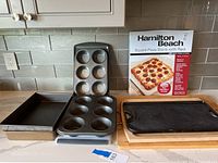Overview of the baking and cooking items arranged on a countertop showing the Le Creuset grill pan, baking pans, and cutting boards.
