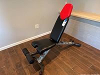Full angled side view of the Bowflex adjustable weight bench showing the foot rests, padded seat and incline backrest.