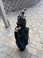 Full view of black and blue golf bag standing upright with clubs inserted