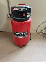 Full view of red Husky air compressor with black top and red handle.