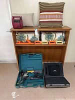 Full view of wooden shelf displaying all items: jump starter, pillows, bins, floats, tool cases