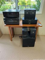 View of all audio components and speakers placed on and around the wooden table near a window.