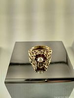 Front view of the antique 9K gold Brutalist ring showing the pearl center surrounded by rubies and detailed openwork gold band.