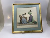 Framed vintage art print showing two women in historical dress, gold trimmed frame with blue and gold double matting.