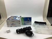 Photo showing 7 Nintendo Wii game cases stacked and one PlayStation 1 game (Cool Boarders 2) in front. Front and side of cases visible. Also shown are a black wired microphone and 2 wrist straps for Wii controllers, plus two transparent disc cases.
