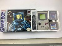 Open original Game Boy box showing console seated in styrofoam along with two game cartridges and power cable