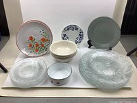 Various assorted dishes shown including floral plates, small bowls, glass plates, and a green pattern plate.