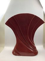 Front view of vintage burgundy ceramic vase showing fan-shaped top and embossed curved line design.