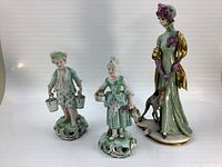 Group shot of three porcelain figurines: boy, girl, and woman