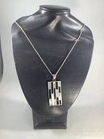 Full length photo of the silver chain with pendant closed on display bust showing entire necklace and pendant design pattern.