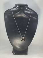 Front view of the necklace with heart pendant displayed on black bust stand.