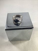 Front and angled view of vintage sterling silver ring with blue lapis stone on a reflective cube.