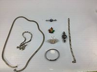 Full assortment of vintage sterling silver jewelry laid out on a white surface. Items include necklaces, bracelets, pins, and brooches in various designs.