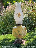 Full view of the Victorian oil lamp showing white glass chimney with floral decoration, brass base, and yellow hand-painted floral glass reservoir.