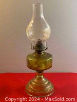 Full view of antique brass oil lamp with etched glass chimney on red background.
