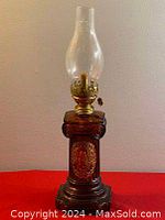 Full view of the antique oil lamp showing amber glass body, brass burner, and clear glass chimney.